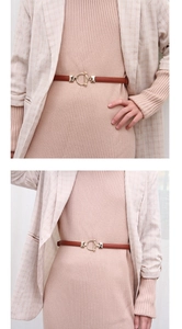 Detail of brown leather skinny belt with gold round buckle on pink knitted dress