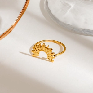 Detailed view of a gold-plated stainless steel ring with a sunburst geometric design