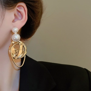 Detail of elegant gold-tone earrings with pearls and irregular hammered metal rings