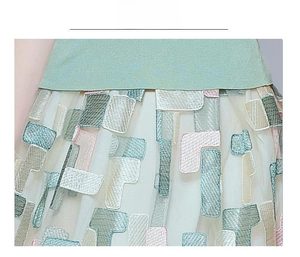 Detail of mint green knit fabric with white mesh and colorful geometric embroidery