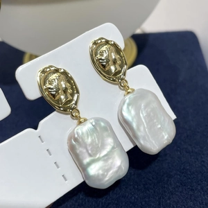 Close-up of baroque freshwater pearl earrings with vintage golden relief carving