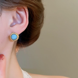 Detailed view of 18k gold plated earring with turquoise and red stones on ear