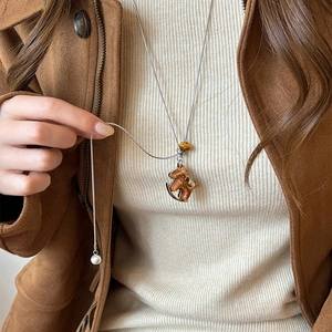 Long collier vintage avec pendentif cheval à bascule marron et perle sur un pull