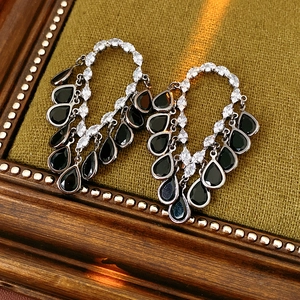 Macro shot of silver needle drop tassel earrings with dark metal and black teardrop gems