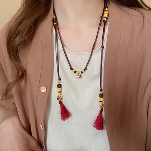 Macro detail of wooden beads, golden metal charms and red silk tassels on the waist chain