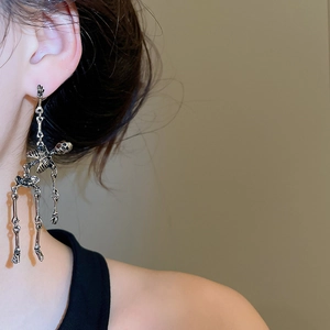 Close-up of gothic skull tassel earrings on a model showing detailed metallic texture