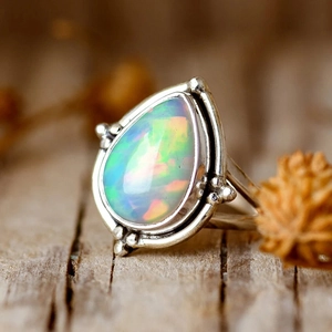 Détail macro d'une bague opale en goutte avec reflets colorés et monture vintage