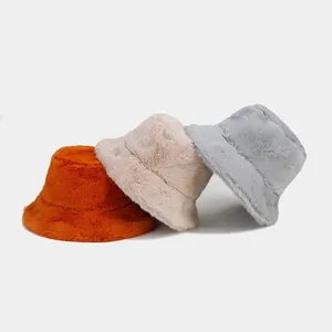 Close-up of fluffy faux fur bucket hats in orange, beige, and grey for winter warmth