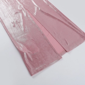 Dettaglio del tessuto rosa metallizzato lucido e spacco laterale sull'orlo dell'abito