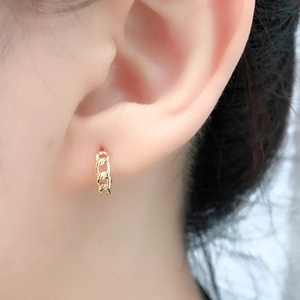 Macro shot of gold chain textured hoop earring made of S925 sterling silver on earlobe