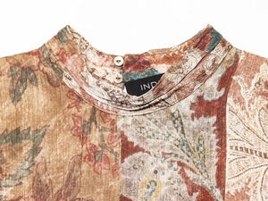 Détail de la texture fleurie en mousseline et fermeture à bouton blanc sur le col