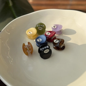 Detailed set of eight colorful billiard-themed mini hair claws in a ceramic bowl