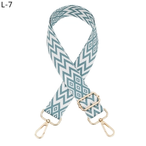 Detail of adjustable bag strap featuring blue and white geometric jacquard pattern with gold hooks