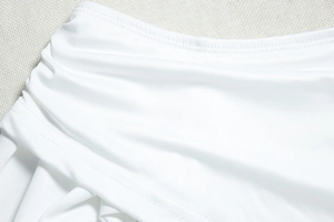 Close-up of white elastic dress showing side ruching details and neat double stitching