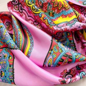 Macro detail of silk scarf featuring pink paisley and architectural patterns with a smooth texture