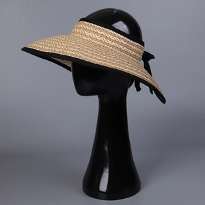 Detail of beige straw visor hat with black bow and elegant woven texture for sun protection