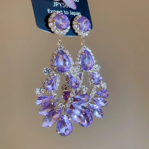 Macro view of luxurious purple crystal cluster drop earrings with sparkling rhinestone borders
