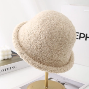 Beige plush French-style winter bucket hat displayed on a modern metal stand