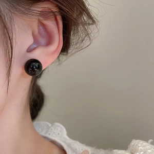 Detailed close-up of a minimalist black round stud earring worn on model for a refined look