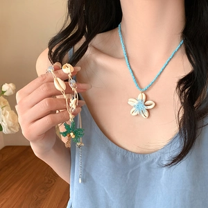Collier de perles en céramique bleue avec fleur en coquillage et bracelet palmier
