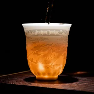 Dehua white porcelain tea cup with embossed dragon motif and warm translucent glow