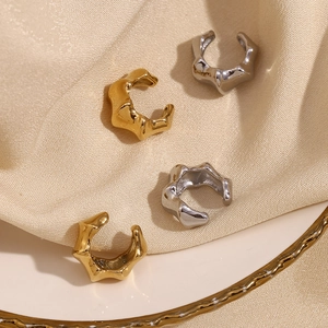 Detailed view of irregular 18K gold and silver bamboo style ear cuffs on silk fabric