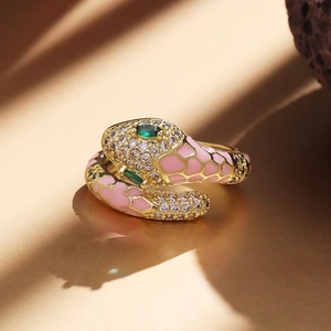 Detail of pink enamel snake ring with green gem eyes and white sparkling crystals