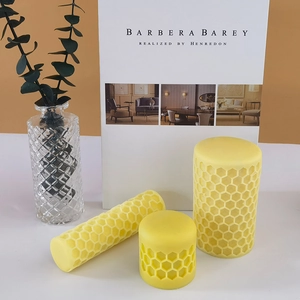 Three sizes of yellow honeycomb textured pillar candles displayed in a modern home interior
