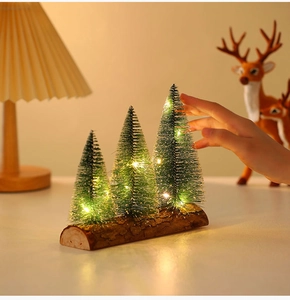 Close-up of three mini flocked Christmas trees with warm LED lights on a wooden base