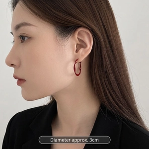 Close-up of red twisted lacquer hoop earring with a 3cm diameter on model ear