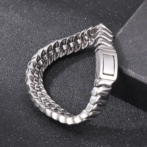 Macro detail of polished silver keel chain bracelet with wave pattern on gray sand texture