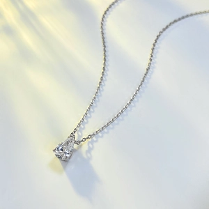 Macro view of a teardrop cut pear pendant on a delicate silver chain with soft shadows