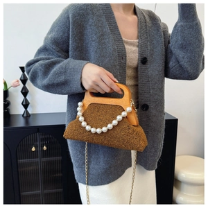 Detailed close-up of brown faux fur handbag with wooden handle and pearl chain strap