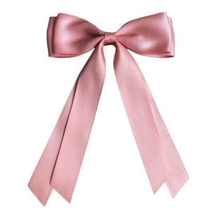 Detail of a large pink double-layered satin ribbon bow hair clip with flowing streamers