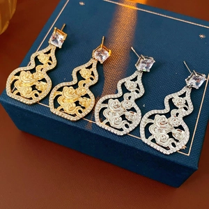 Close-up of gold and silver gourd earrings with cubic zirconia in a jewelry box