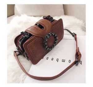 Detailed side view of brown faux leather crossbody bag with rivet details and chain strap