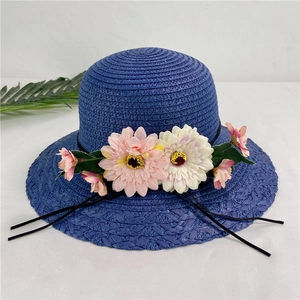 Close-up of blue straw sun hat featuring colorful floral decor and black chin straps