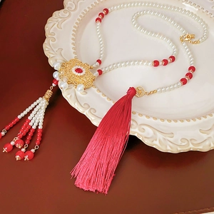 Detailed macro view of Chinese phoenix lock necklace with red tassels and gold metalwork
