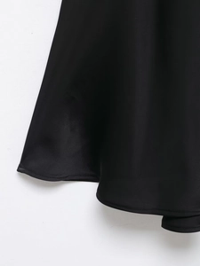 Détail de l'ourlet de la robe en satin noir élégant montrant la texture lisse