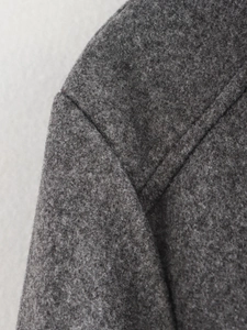Nahaufnahme der professionellen Naht und Textur der dunkelgrauen Tweed-Jacke