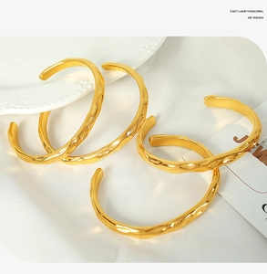 Detailed view of four irregular hammered gold texture cuff bracelets on white silk