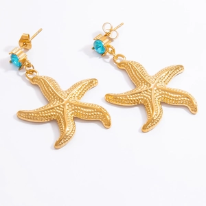 Macro detail of starfish earrings with blue zircon stones and gold finish texture