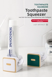Detail of knob-style toothpaste squeezer in white and green with gold trim and wall mount