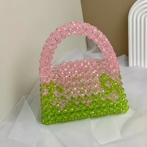 Detail of pink and green beaded handbag with watermelon color scheme on white fabric