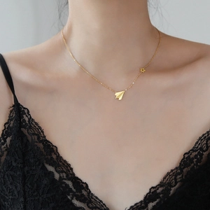 Elegante collana dorata con aereo origami e ciondolo a stella su una modella