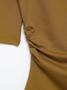 Detail shot of ginger yellow ribbed knit fabric featuring side ruching and seam details