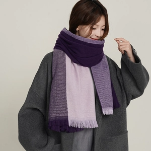 Elegant two-tone purple knit scarf with fringe trim worn by a fashion model on plain background