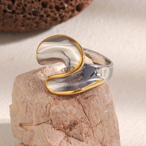 Vue macro d'une bague torsadée bicolore argent et or sur un fond de pierre naturelle