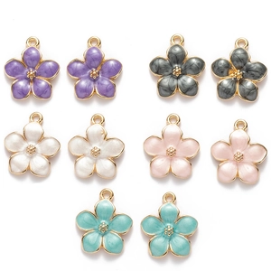 Flat lay of alloy cherry blossom pendants in five pastel colors with gold hanging loops