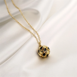 Detail of gold hollow heart pendant with black enamel heart patterns on white silk cloth